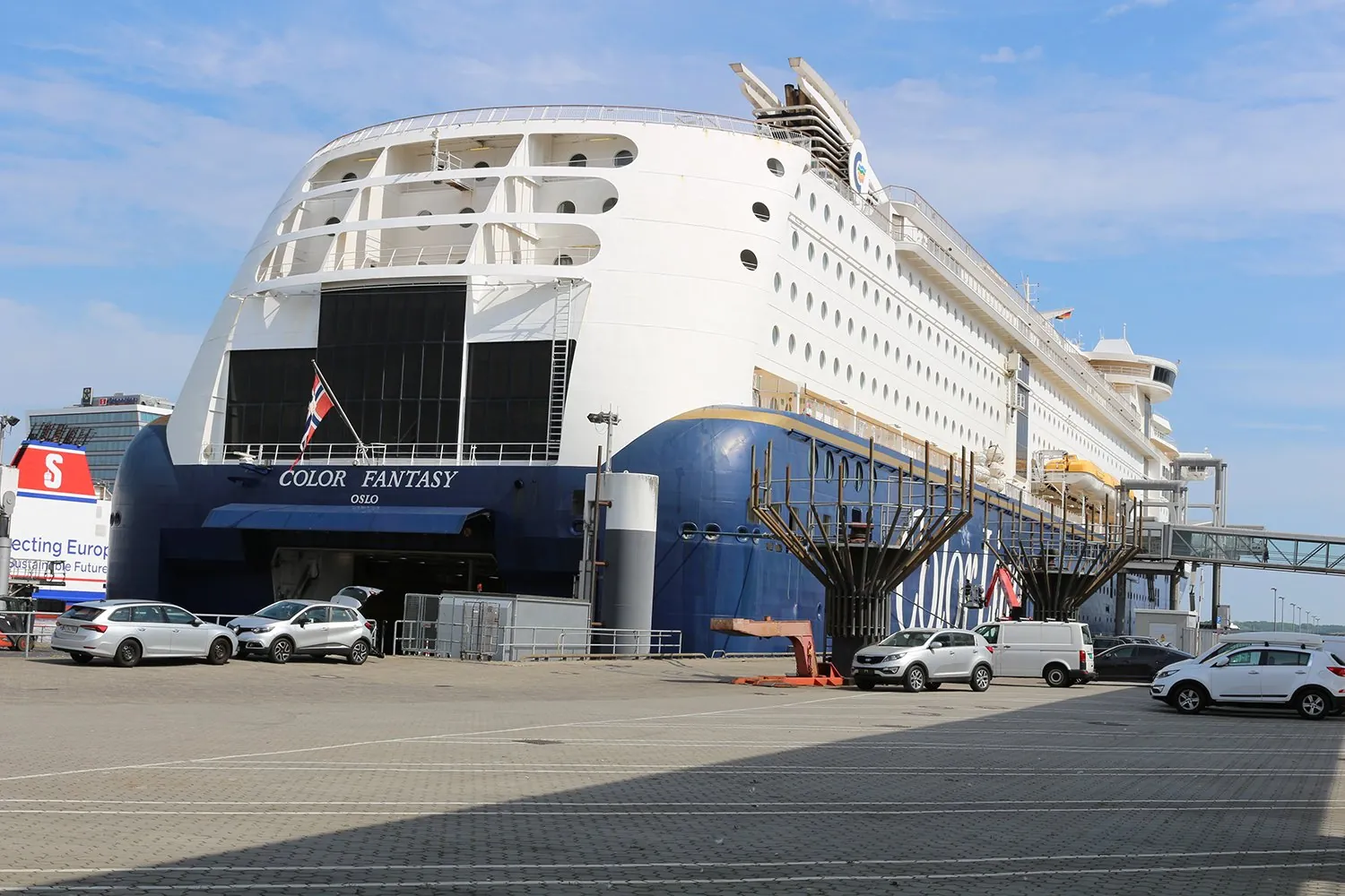 Le Color Fantasy à quai à Kiel, avec des voitures garées sur le terminal devant la coque bleue