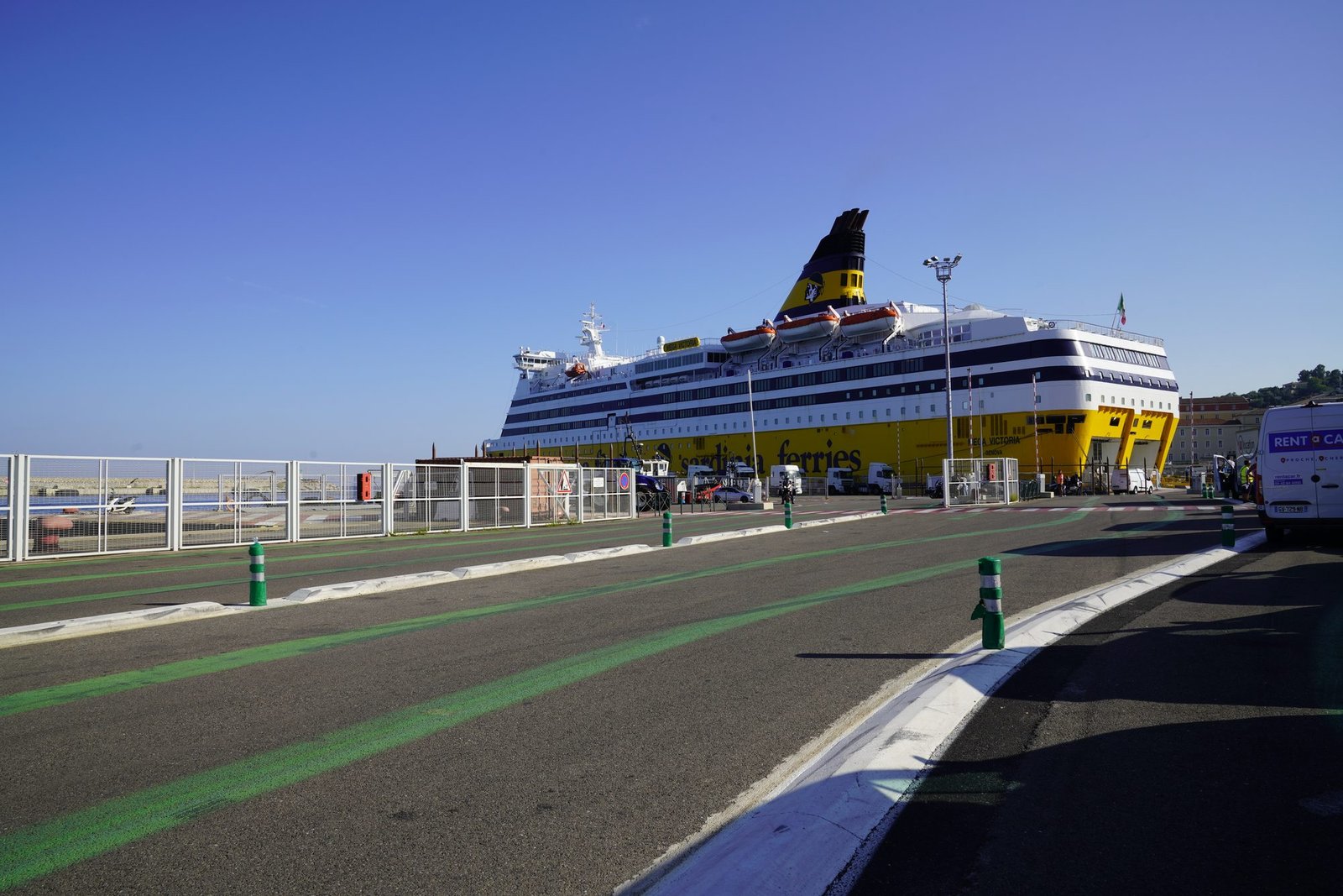 Le ferry Mega Victoria de Corsica Ferries, coque jaune et cheminée bleu foncé, à quai à Bastia, vu depuis le parking d’embarquement